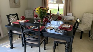 Comedor con una mesa de madera oscura dispuesta para cuatro personas, rodeada de sillas tapizadas.