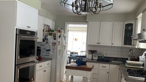 Una cocina moderna con armarios blancos, electrodomésticos de acero inoxidable, suelo de madera y alfombra estampada.