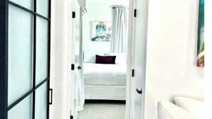 A hallway leading to a bedroom with a bed, a painting on the wall, and a white sofa. - 2 Seasons-4 Bedroom 2 Baths - 2Separate Apartments (Miami)