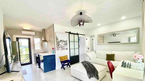 A modern living room with a white sofa, a red chair, and a dining area with a white table and chairs. - 2 Seasons-4 Bedroom 2 Baths - 2Separate Apartments (Miami)