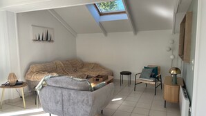 A modern living room with a sloped ceiling, a sofa, a chair, a small table, and a floor lamp. - Beachside House for 9 with Garden & Bikes - Near Port Navalo, Arzon (Arzon)
