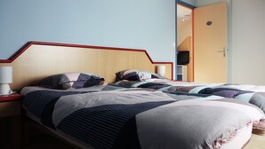 Una cama doble con cabecera de madera, dos mesitas de noche con lámparas y un armario al fondo.