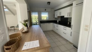 Una cocina moderna con armarios blancos, encimera de madera y vistas al exterior con vegetación.