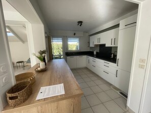 A modern kitchen with white cabinets, a wooden countertop, and a view of greenery outside. - Beachside House for 9 with Garden & Bikes - Near Port Navalo, Arzon (Arzon)