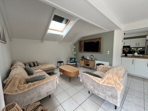 A modern loft-style living area with a skylight, a flat-screen TV, and a kitchenette. - Beachside House for 9 with Garden & Bikes - Near Port Navalo, Arzon (Arzon)