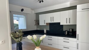 A modern kitchen with white cabinets, a black countertop, and a window with a view of greenery. - Beachside House for 9 with Garden & Bikes - Near Port Navalo, Arzon (Arzon)