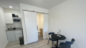 A compact kitchen with modern appliances, a dining area with a small table and chairs, and a sliding door leading to a bathroom. - Excellent location Miami Brickell Studio 1.7 Miles from the Beach (Miami)