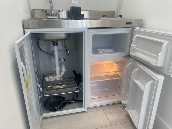 A compact kitchen with a built-in sink, a stove, and a refrigerator.