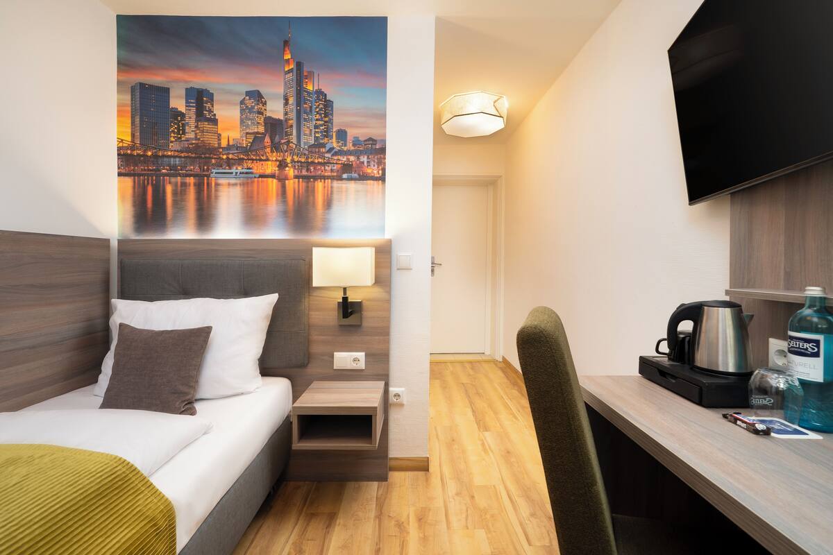 Une chambre d’hôtel équipée d’un lit, d’un bureau, d’une télévision, d’une machine à café et d’une bouteille d’eau.