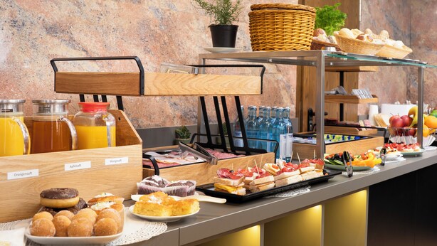 Un bufé con diversos alimentos, entre ellos, pasteles, frutas y bebidas.