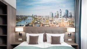 Habitación de hotel con una cama grande, dos lámparas de noche, vistas a la ciudad y un cabecero de madera.