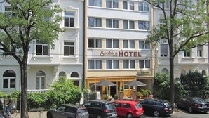 Un hotel de varios pisos con un llamativo letrero que dice 'Sophien Hotel', que presenta un estilo arquitectónico clásico con ventanas simétricas y una entrada central.