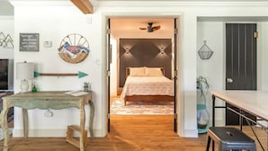 A room with a bed, a table, and a door leading to another room. - Near Red Rocks & Trails • Private Luxury Home (Wheat Ridge)