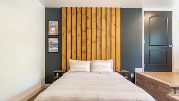 A bedroom with a large bed, wooden headboard, two bedside tables, and a door. - Near Red Rocks & Trails • Private Luxury Home (Wheat Ridge)