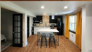 A compact kitchen with a central island, black cabinets, and a window with yellow curtains. - Near Red Rocks & Trails • Private Luxury Home (Wheat Ridge)