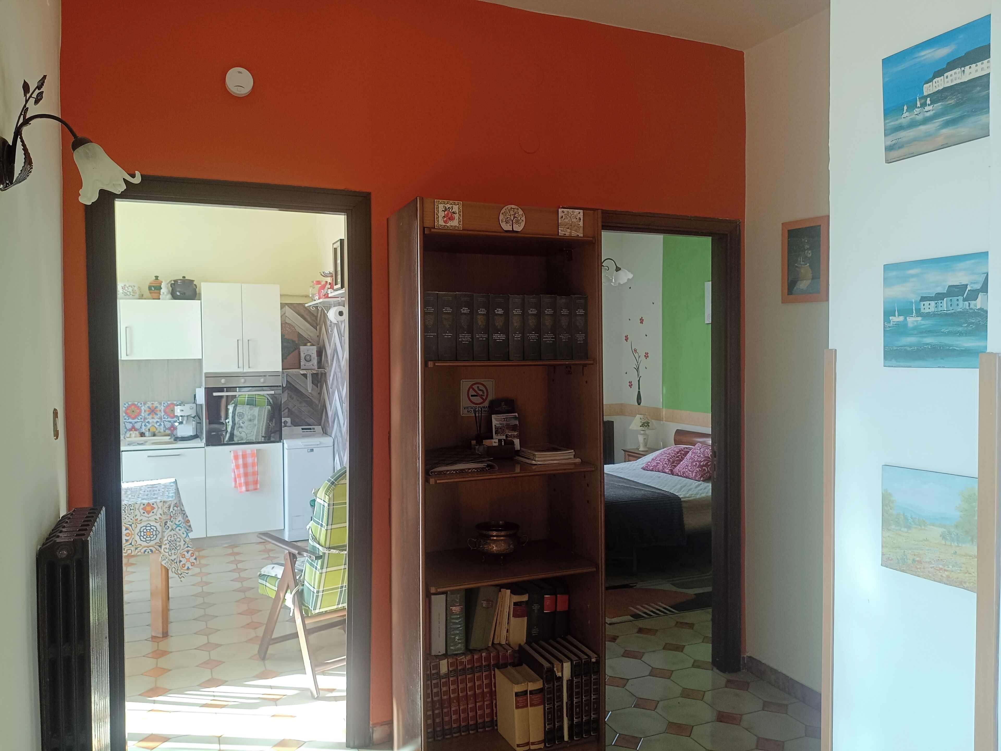 Une pièce avec une bibliothèque, un lit et une vue sur la cuisine.