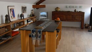 A dining area with a long wooden table, chairs, and a decorative runner. There is a television on a stand and a wooden cabinet with decorative items. - 2 room loft Rue de la Croix / Cannes (Cannes)