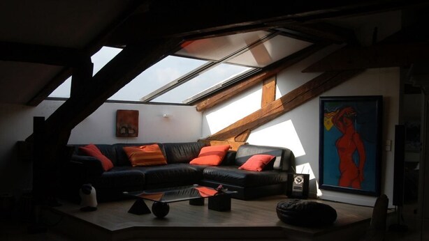 A loft-style living room with a black leather sofa, orange cushions, and a skylight. - 2 room loft Rue de la Croix / Cannes (Cannes)