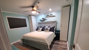 A bedroom with a bed, a nightstand, a ceiling fan, and a wall-mounted decorative piece. - Renovated Oceanview End Unit w/ Use of Hilton Ocean Oak Resort and Amenities (Hilton Head Island)
