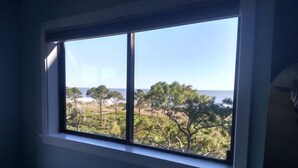 A room with a large window overlooking a beach and trees. - Renovated Oceanview End Unit w/ Use of Hilton Ocean Oak Resort and Amenities (Hilton Head Island)