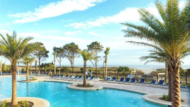 A swimming pool with palm trees and lounge chairs. - Renovated Oceanview End Unit w/ Use of Hilton Ocean Oak Resort and Amenities (Hilton Head Island)