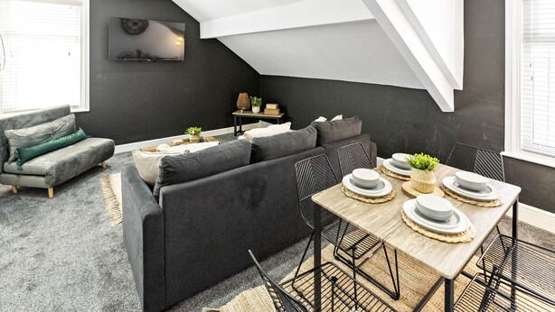 Un espace de vie moderne de style loft, comprenant un coin repas, des murs de couleur sombre et une verrière.