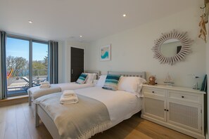 Camera d'albergo con due letti, un'ampia finestra, uno specchio e un tavolino con oggetti decorativi.