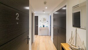 A hallway with a wooden floor, a number '2' sign, a mirror, and a small table with a model ship. - Sea Glass (St Ives)