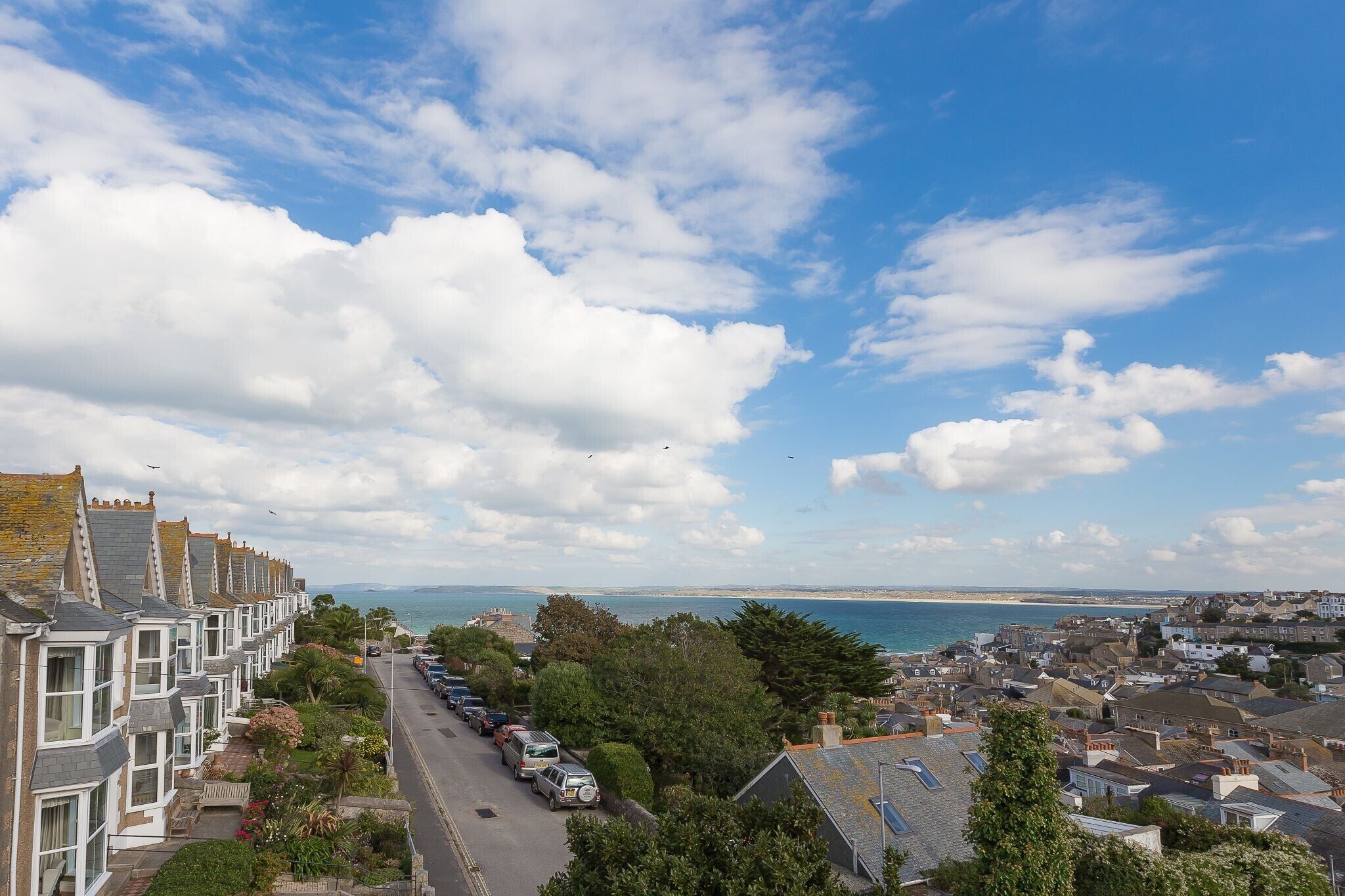 A coastal town with terraced houses, a clear sky, and a view of the sea.
