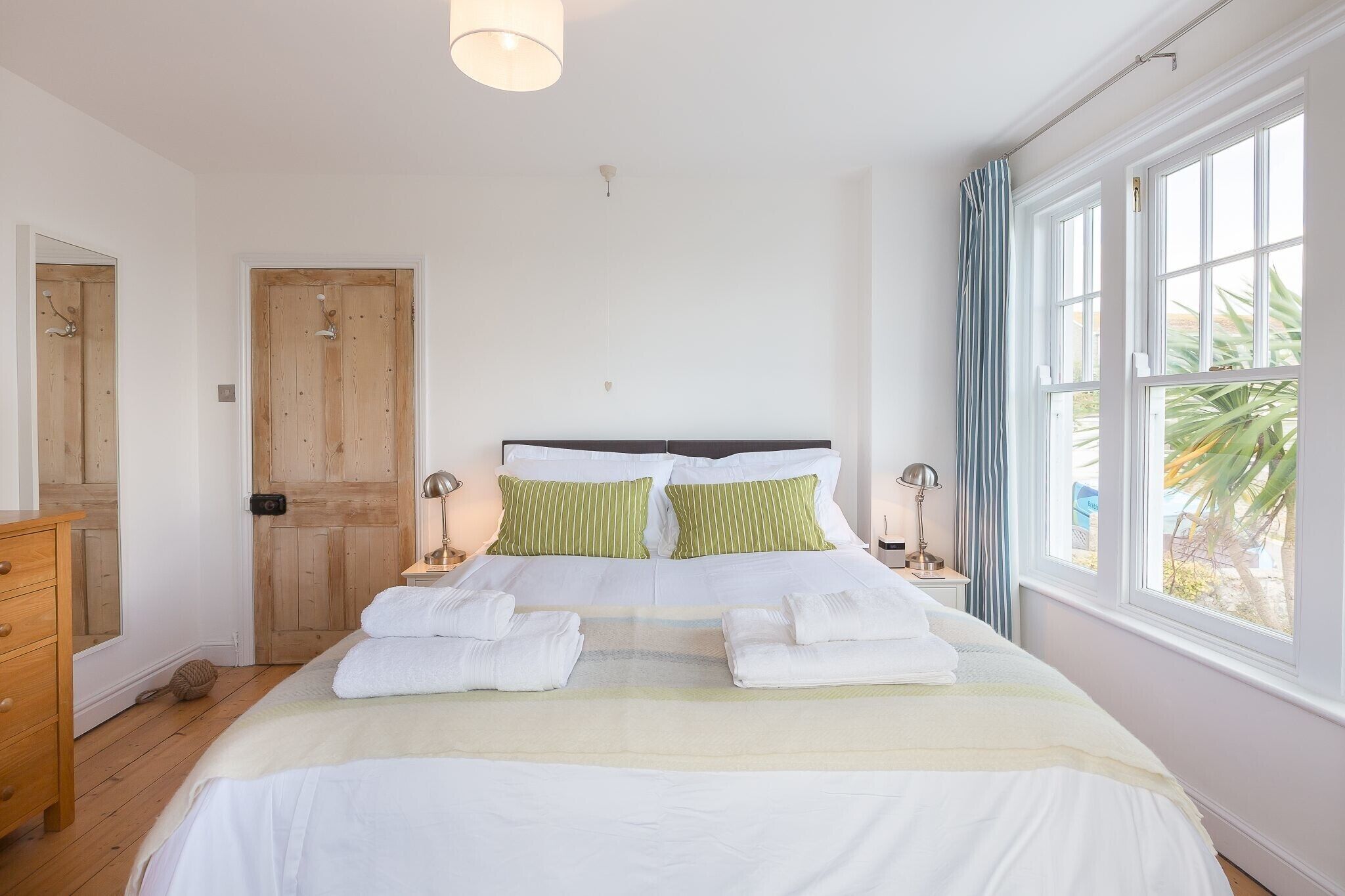 Un dormitorio con una cama grande, una puerta de madera y una ventana con cortinas.