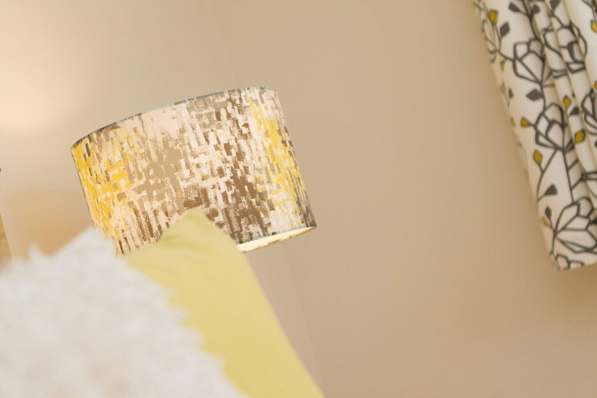 A close-up of a textured, metallic lamp with a yellow base.