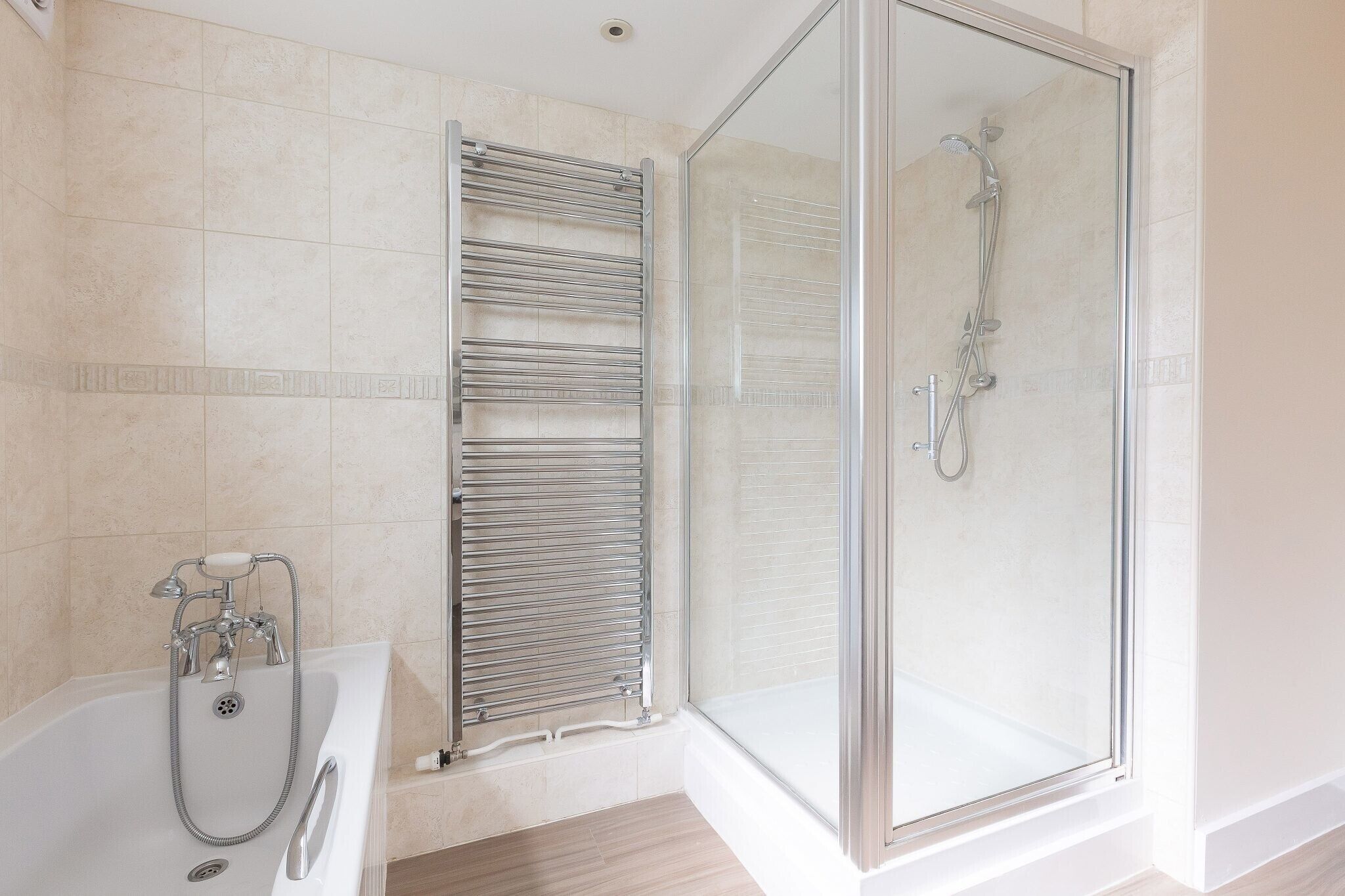 A modern bathroom with a glass-enclosed shower, a standalone bathtub, and a towel rack.