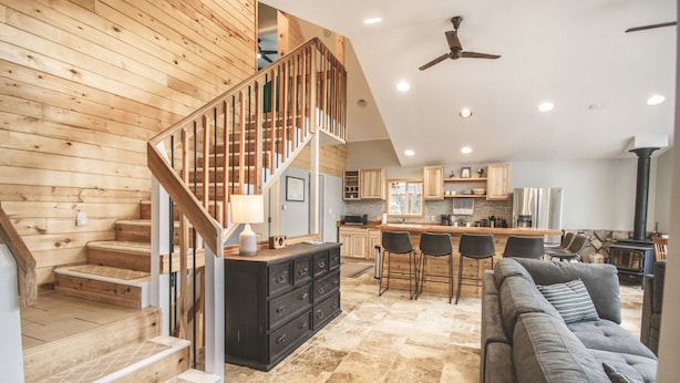 A spacious living area with a wooden staircase, a kitchen with modern appliances, and a cozy seating area.