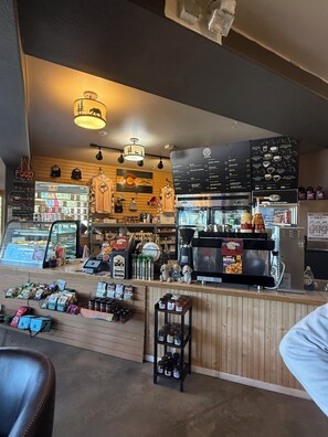 A coffee shop interior with a counter, espresso machines, and a menu board.