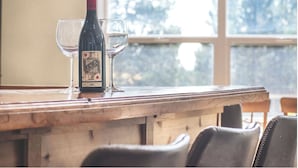 A wooden bar with a bottle of wine and two glasses on it.
