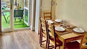 A dining area with a wooden table set for four, a sliding glass door leading to a patio, and a clock on the wall. - Modern, spacious and comfortable 3 bedroom home. (Manchester)
