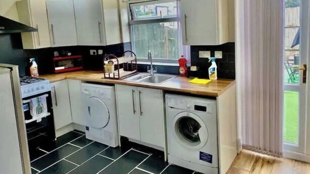 A compact kitchen with a washing machine, a sink, and a window. - Modern, spacious and comfortable 3 bedroom home. (Manchester)