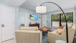 A living room with a ceiling fan, a television, a sofa, a coffee table, and a window with blinds. - "Flamingo Feliz" Heated Pool! Close to Beach and 5th Ave. (Naples)