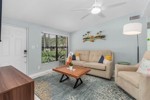 A living room with a wooden coffee table, beige sofa, and a ceiling fan.