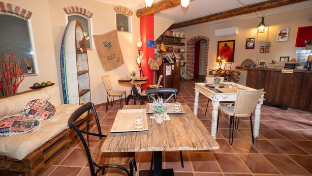 Un comedor acogedor con muebles de madera rústica, una pared de acento roja y una cocina al fondo.