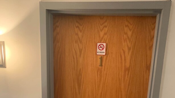 A wooden door with a 'No Smoking' sign and a door number '1'.
