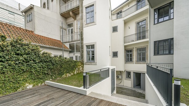 Un edifici residencial de diversos pisos amb balcons, una terrassa de fusta i un bord.