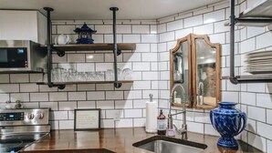 A kitchen with white tiled backsplash, stainless steel appliances, wooden shelves, and a blue ceramic vase. - Stunning Ground Floor Apartment in Green Ridge. (Scranton)