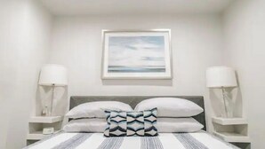 A neatly arranged bedroom with a bed, pillows, bedside tables, and a framed picture on the wall. - Stunning Ground Floor Apartment in Green Ridge. (Scranton)
