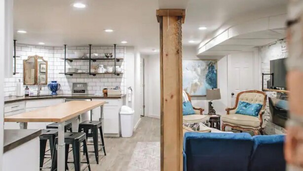 A modern kitchen with white subway tiles, a wooden island, and black bar stools. - Stunning Ground Floor Apartment in Green Ridge. (Scranton)