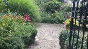 A paved garden path with a metal fence on one side and a variety of plants and flowers on the other. - Nautically themed apartment with Ocean View (Bristol)
