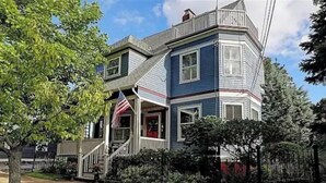 A two-story house with a porch and a small front yard. - Nautically themed apartment with Ocean View (Bristol)