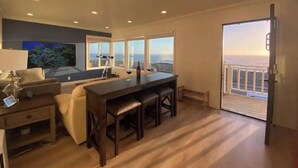 Una sala moderna con un gran ventanal, un comedor y vistas al océano.