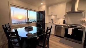 Una cocina moderna con comedor, vistas al atardecer y un ventanal grande.