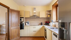 Una cocina compacta con armarios de madera, un microondas, una estufa, una cafetera y un refrigerador.